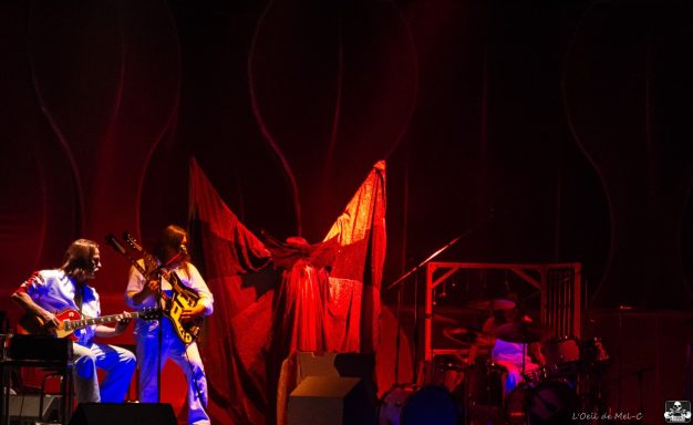 Band performing on stage with colorful lighting and dynamic set design.