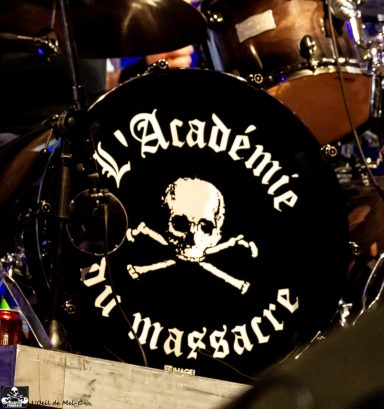 Black drum with the text "L'Académie du massacre" and a skull and crossbones design.