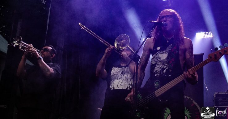 Musicians performing on stage with instruments in a vibrant, lit atmosphere.