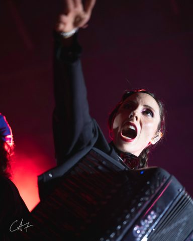 A performer passionately playing an accordion while singing on stage.