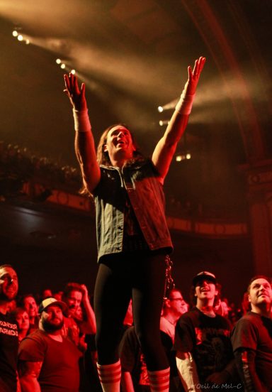 A performer engages the crowd with arms raised during a vibrant concert.