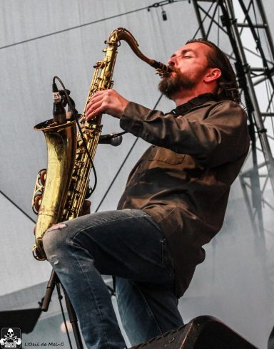 Musician playing a saxophone passionately on stage during a performance.