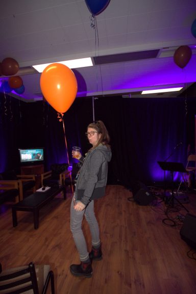 Person with a balloon in a dimly lit room with decorations and a music setup.