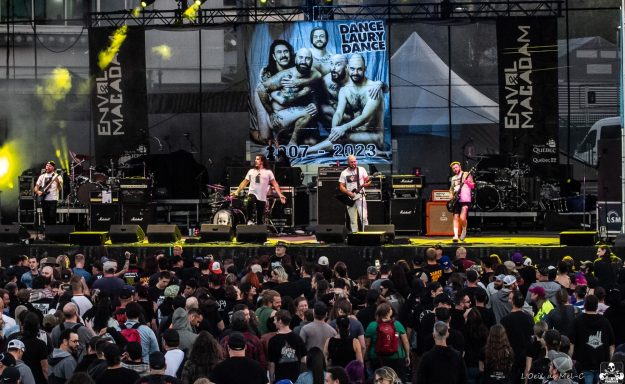 Live band performing on stage in front of a large, enthusiastic crowd.