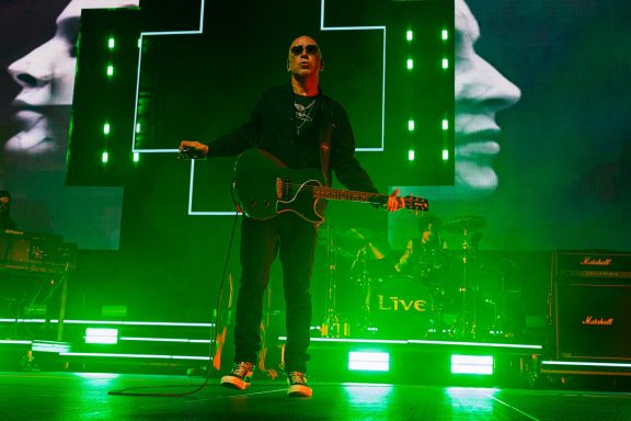 +LIVE+ - Centre Videotron A musician performing on stage with green lighting and large screens in the background.