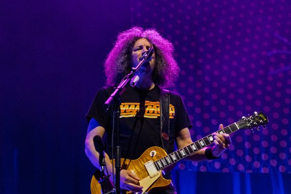 Big Wreck - Centre Videotron A musician with curly hair plays guitar on stage, wearing a black t-shirt.