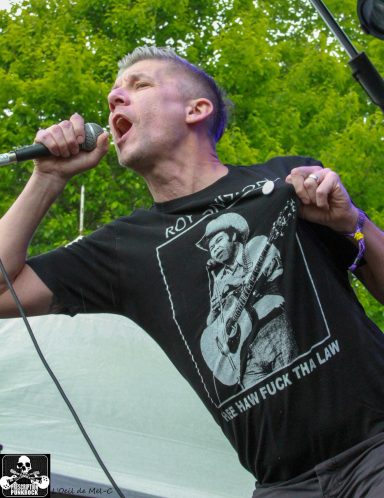 Man singing passionately into a microphone, wearing a T-shirt featuring a musician.