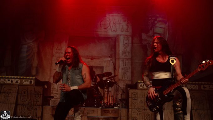 Band performing on stage with dynamic lighting, featuring a singer and a bassist.