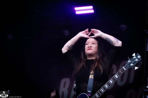 Musician on stage with a guitar, raising hands in a gesture of celebration.