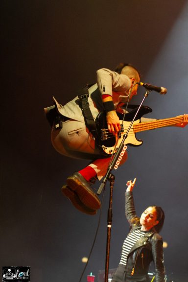 A performer jumps while playing guitar, with another person raising their arm in excitement.