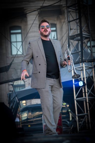 Man in a gray suit and sunglasses performing on stage.