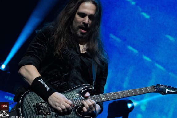 A musician playing electric guitar on stage with dramatic lighting.