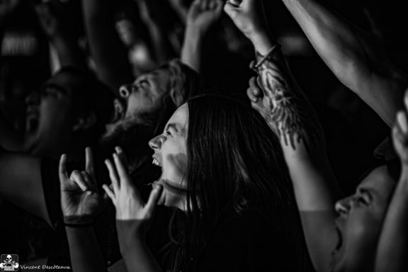 Crowd with raised hands, expressing excitement and energy at a concert.