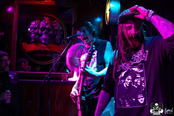 Musicians performing on stage with vibrant lighting in a lively venue.