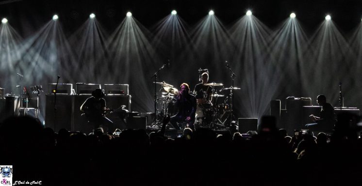 Concert scene with performers on stage and dramatic lighting illuminating the atmosphere.