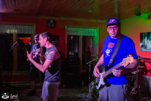 Band performing on stage with a lively atmosphere, featuring a vocalist and bassist.