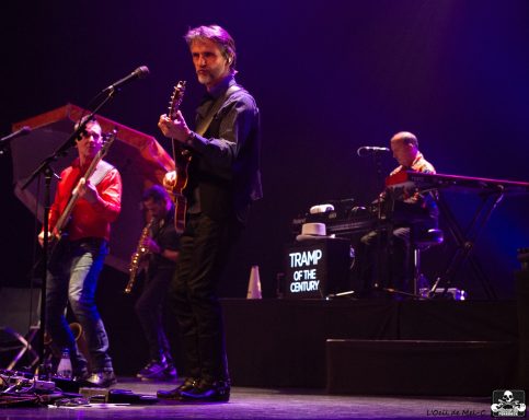 Musicians performing on stage, with a guitarist and keyboardist in focus.