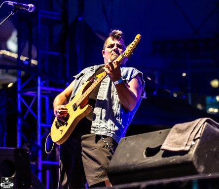 Musician playing guitar on stage at a live performance.