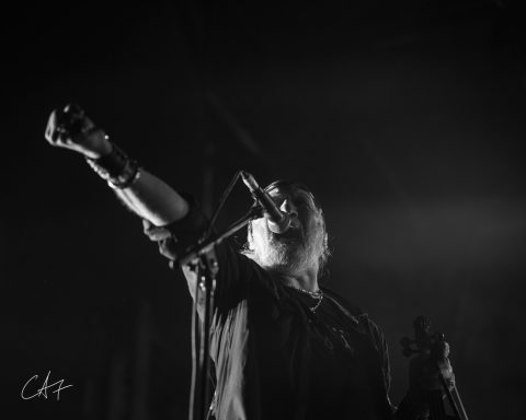 A lead singer performing passionately on stage with a microphone.