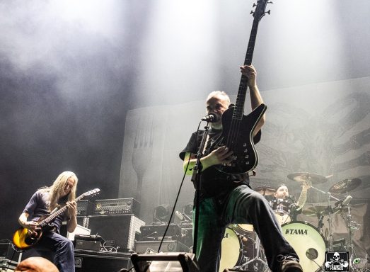 Musicians performing on stage with guitars and drums in a rock concert setting.