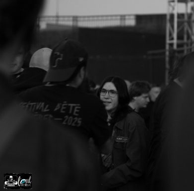 A crowd scene with two people in conversation, one wearing a cap and the other smiling.