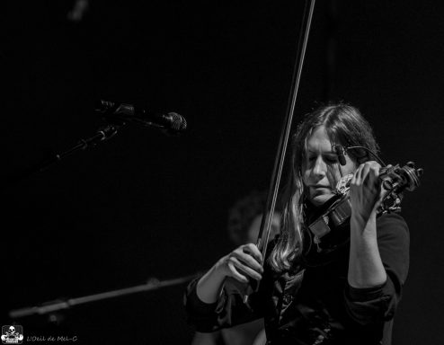 A musician playing the violin on stage with a focused expression.