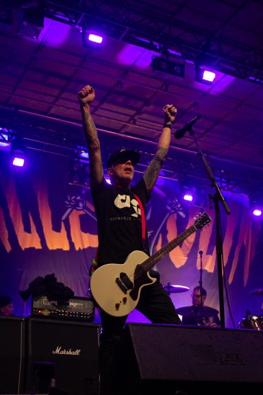 Millencolin - Red Bridge Fest 2026 A musician on stage with a guitar, raising arms in celebration, with purple lights in the background.