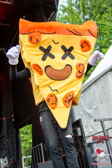 Person in a large pizza costume with a smiling face and cartoonish pepperoni.