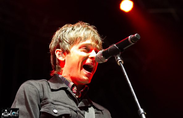 Singer performing passionately on stage with dramatic lighting.
