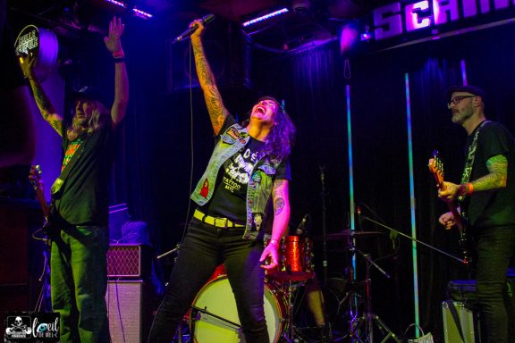 A live band performing on stage, with a singer and musicians actively engaging the crowd.