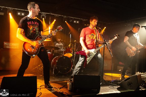 Three musicians performing on stage with colorful lights.