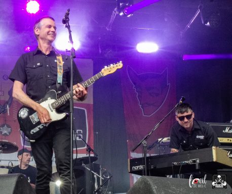 A guitarist and keyboardist performing on stage at a music festival.