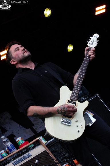 A musician playing an electric guitar on stage, focused and performing.