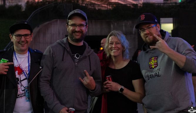 Four friends smiling and posing together outdoors at sunset.