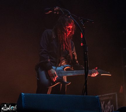 Musician playing an electric guitar on stage with dramatic lighting.