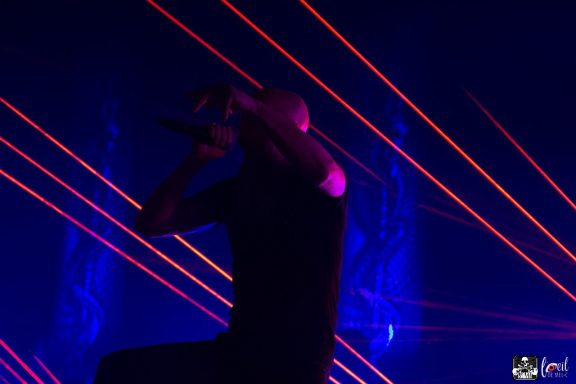 A performer on stage with laser lights in a dark setting.