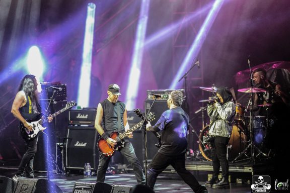 Rock band performing on stage with vibrant lighting and instruments.