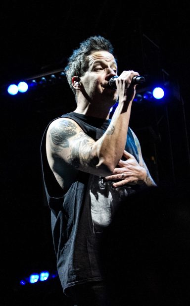 Singer performing on stage with a focused expression, microphone in hand.