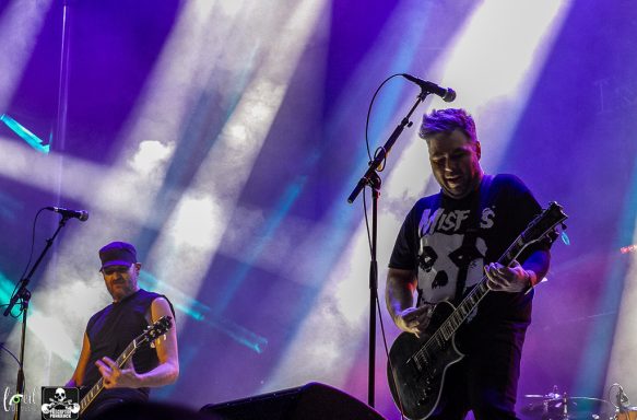Two musicians performing on stage with colorful lights in the background.