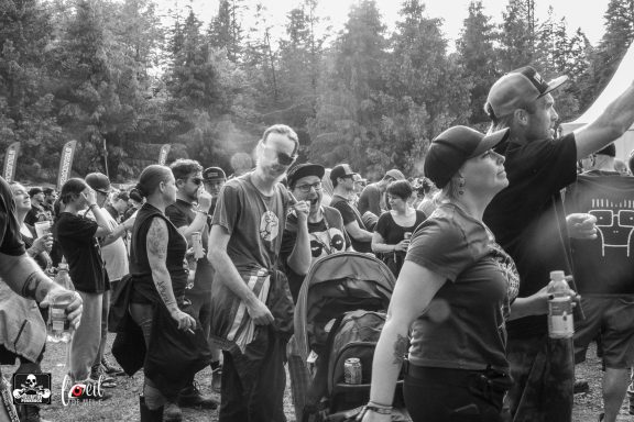 Crowd of people enjoying an outdoor event surrounded by trees.