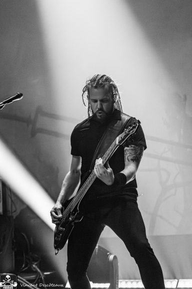 A musician playing guitar on stage with dramatic lighting in black and white.