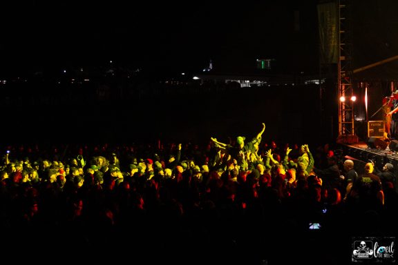 Crowd at a concert illuminated by colorful lights during a nighttime performance.
