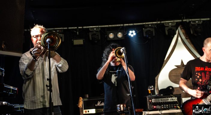 Dead Bob - La Source de la Martinière Musicians playing trumpets on stage with instruments and dramatic lighting.