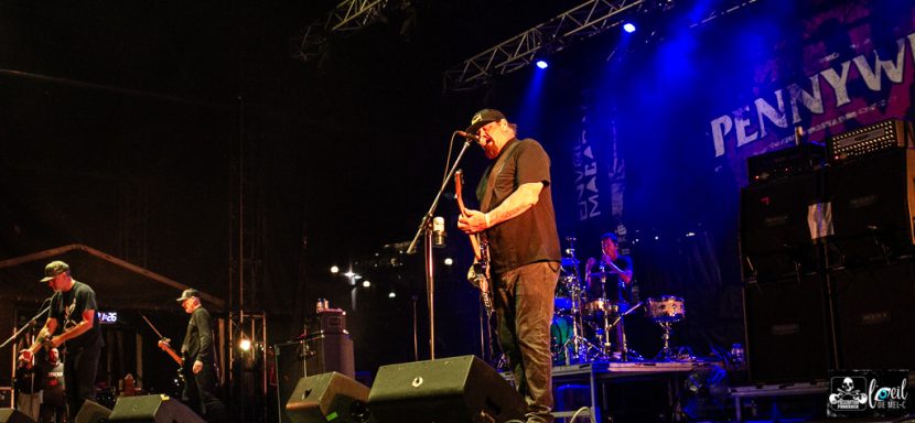 A live band performs on stage with instruments and vibrant stage lighting.