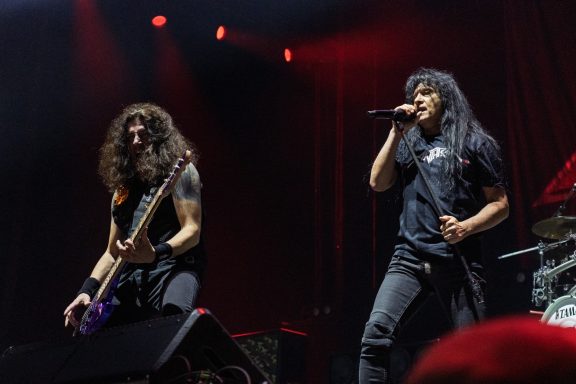 Two musicians performing on stage, one playing guitar and the other singing.