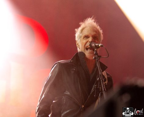 A singer in a leather jacket performing energetically with a microphone.