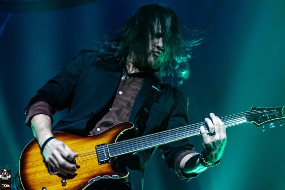 Musician playing electric guitar under vibrant stage lighting.