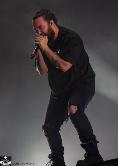 A musician performing on stage, holding a microphone with intense expression.