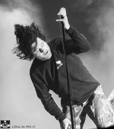 A performer singing passionately, with wild hair and a microphone, in a dynamic pose.