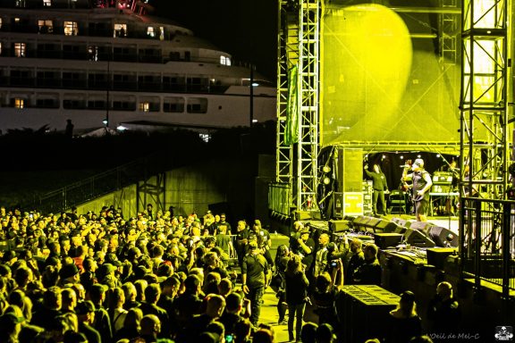 Crowd enjoying a musical performance at a night concert with yellow lighting.
